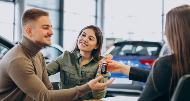 Young couple talking to a sales person in a car showroom